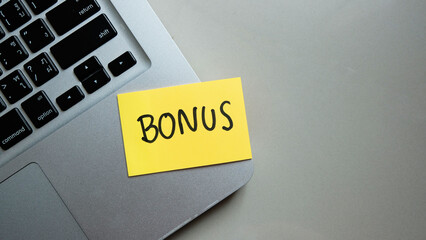 Bonus message concept written post it on laptop keyboard.	