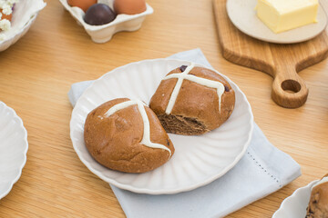 Hot cross buns on white plate on wooden table. Happy Easter