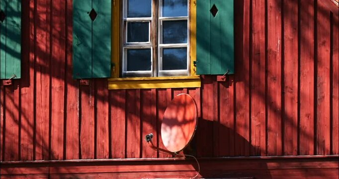 Colorful wooden house with window and satellite dish in warm sunlight