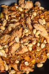 Wok noodles with chicken meat and sesame and peanut in bowl on dark stone background 