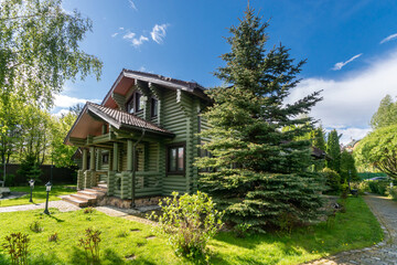 A delightful summer landscape on a private territory with a two-storey wooden house .Sunny, clear day.