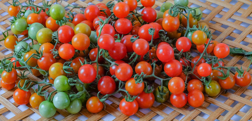 Fresh Red tomatoes with green stems on bamboo basket.