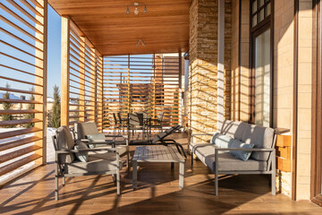 The outdoor space features comfortable gray seating and a coffee table with blue cushions. Sunlight...