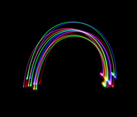 A long exposure photograph of colourful lights in a rainbow arc shape against a black background