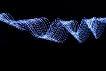 A long exposure photograph of vibrant electric blue light in swirl patterns of motion against a...