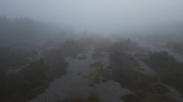 Low forward drone flight over the misty flint fields at Mukran, R&uuml;gen Island, Germany, cinematic aerial shot with strong fog creating a mystical and atmospheric natural landscape