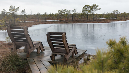 
two wooden benches on a platform by a water-covered area.