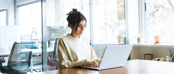 Young latina hispanic business woman working on laptop computer in office. Focused Indian...