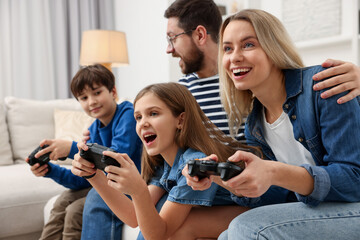 Fototapeta premium Happy family playing video games on sofa at home, selective focus