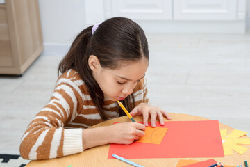 Girl drawing card at table indoors. Art and craft