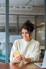 Hispanic business woman manager using cell phone mobile app, laptop. Smiling Latin or Indian...