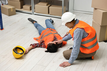 Accident at work. Man checking pulse of his unconscious colleague in warehouse