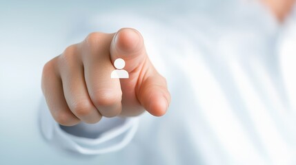 Obraz premium A hand with a white silhouette of a person on the index finger points directly forward against a blurred light blue and white background.