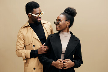 Stylish couple wearing trendy outfits, smiling and enjoying each other s company against a neutral beige background, reflecting modern fashion and joyful emotions
