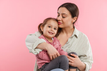 Portrait of mother with her cute daughter on pink background