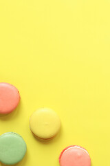 Bright French macarons on yellow background, top view. Assortment of multi-colored macarons with different flavors. Delicious pastries, flat lay. Food background. Sweets
