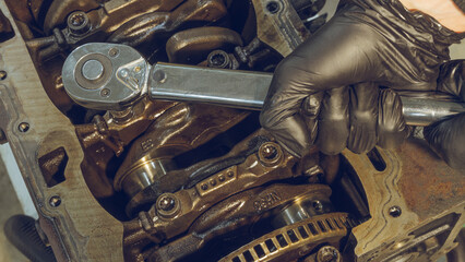 A mechanic working on a car engine in a well-equipped auto repair shop. Car Engine Repair. Mechanic using wrench while working on car engine at garage workshop. Repairing engine in auto repair shop