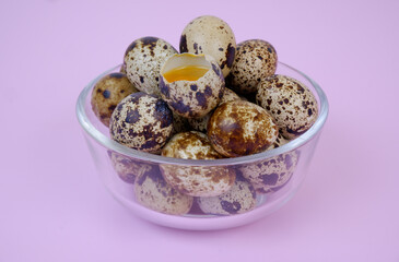Raw quail eggs in wooden bowl on pink background