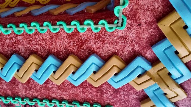 A red carpet with a blue and green border. The carpet is made of plastic