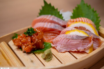 Salmon Sashimi set served on wooden sushi boat, with lemon and wasabi