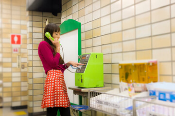 公衆電話をかける女性