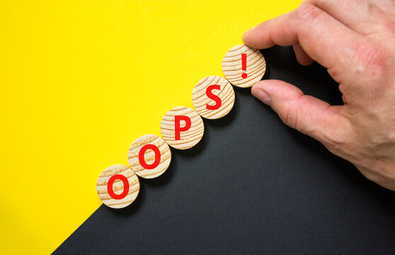 Oops symbol. Concept word Oops on beautiful wooden circles. Beautiful yellow and black background. Businessman hand. Business lifestyle oops concept. Copy space.