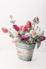 bouquet of pink , lilac, white tulips in a vintage zinc pot with flower pattern