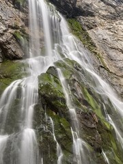 Fototapeta premium Waterfall cascading over moss-covered rocks on rugged cliffside 