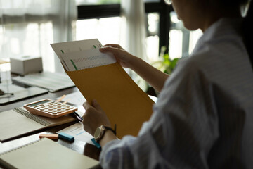 the businessman is sitting at a desk with a calculator and a stack of papers. She is looking at the...