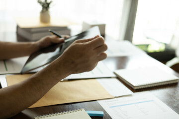the businessman is sitting at a desk with a calculator and a stack of papers. She is looking at the...