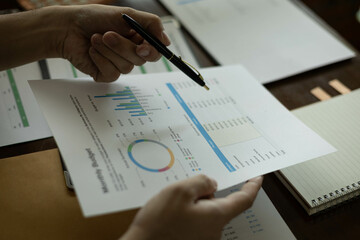 the businessman is sitting at a desk with a calculator and a stack of papers. She is looking at the papers and seems to be deep in thought
