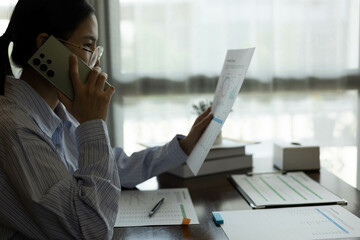 the businessman is sitting at a desk with a calculator and a stack of papers. She is looking at the...