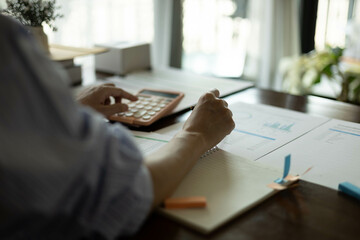 the businessman is sitting at a desk with a calculator and a stack of papers. She is looking at the...