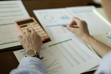 the businessman is sitting at a desk with a calculator and a stack of papers. She is looking at the papers and seems to be deep in thought

