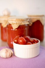 Homemade canned salted tomatoes jar on table with garlic and spices on white background. Food stock. Healthy food. Harvesting. vertical.