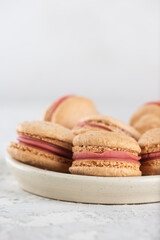 Vegan homemade caramel macarons with raspberry cream on shea butter. Sugar, lactose and gluten free. Vertical orientation.