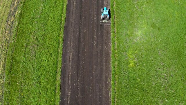 Aerial View of a Blue Tractor Plowing a Field for Crop Preparation