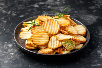 Homemade Crinkle Cut French Fries on plate with rosemary. Crispy potato fries snack,