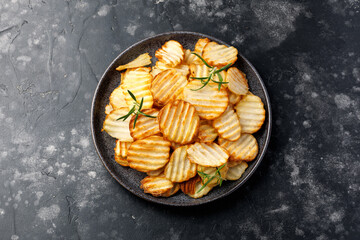 Homemade Crinkle Cut French Fries on plate with rosemary. Crispy potato fries snack,