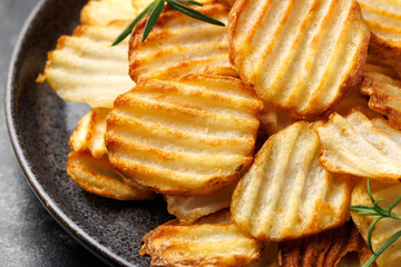 Homemade Crinkle Cut French Fries on plate with rosemary. Crispy potato fries snack,