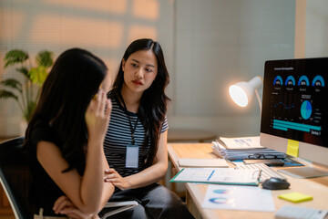 Asian businesswomen comforting colleague after bad news in office at night