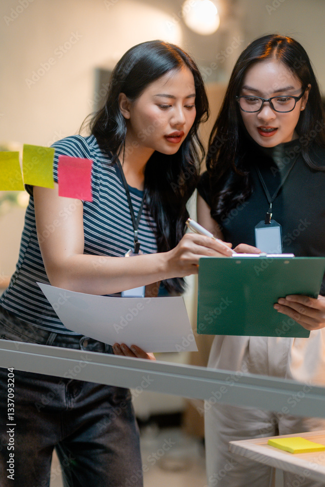 Poster two businesswomen discussing and analyzing financial data using sticky notes in office