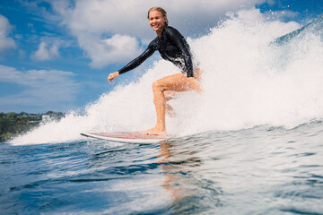 Surfgirl surfer riding a perfect breaking wave on a sunny day