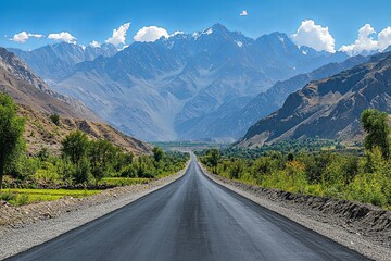 Fototapeta premium A long asphalt road leading towards majestic snow capped mountains