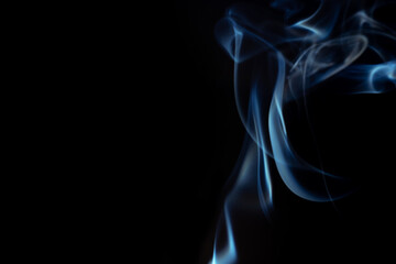 Wispy blue smoke wave flowing against a black background, creating a sense of mystery. Abstract and atmospheric concept. Concept of mystery and creativity. Swirling, writhing smoke to overlay