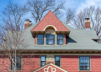Elegant red-shingled dormer on a historic family home on a winter day in Brighton, Massachusetts,...