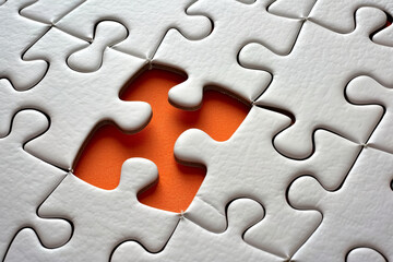 A white puzzle piece about to fit into place against an orange background, symbolizing problem-solving, connection, and completion. AI-generated.