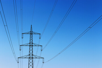 Bottom-up view of an electrical transmission line with blue sky in the background