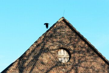 Bottom-up view of a farmhouse building with bird flying away