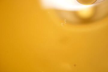Abstract Close Up of Golden Liquid with Bubbles and Light Reflections